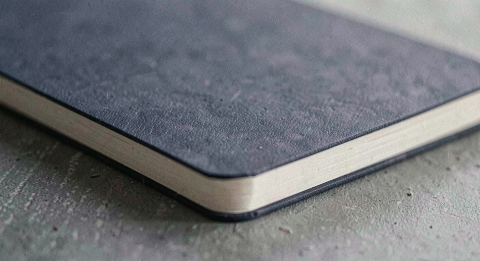 A quiet macro scene of notebook material with indigo texture and an unbleached edge